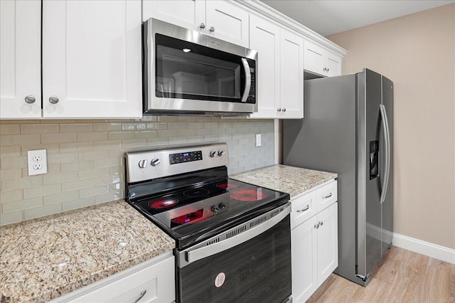 kitchen with light stone countertops, tasteful backsplash, stainless steel appliances, light hardwood / wood-style flooring, and white cabinets