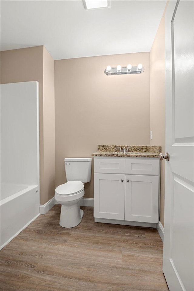 bathroom featuring a tub to relax in, vanity, wood-type flooring, and toilet