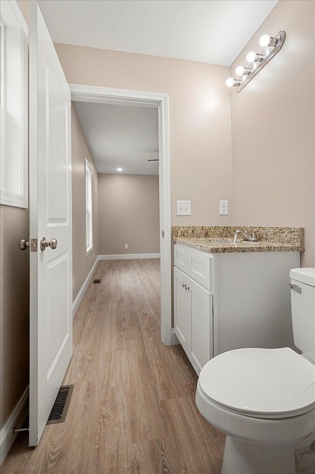 bathroom with wood-type flooring, vanity, and toilet