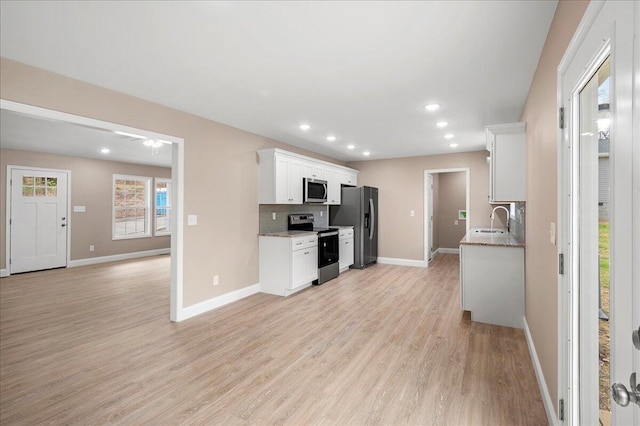 kitchen with white cabinetry, sink, stainless steel appliances, tasteful backsplash, and light wood-type flooring