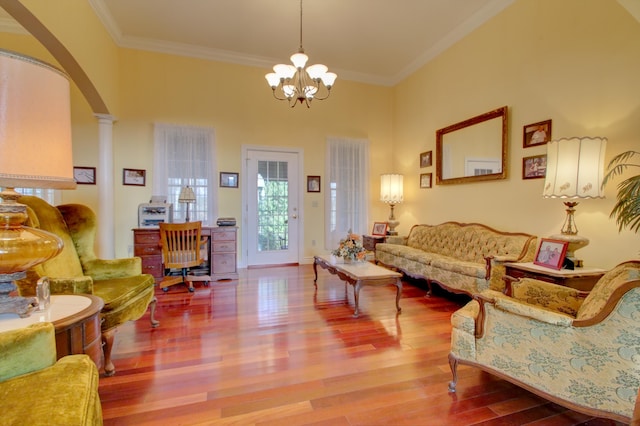 living room featuring a chandelier, decorative columns, hardwood / wood-style flooring, and crown molding