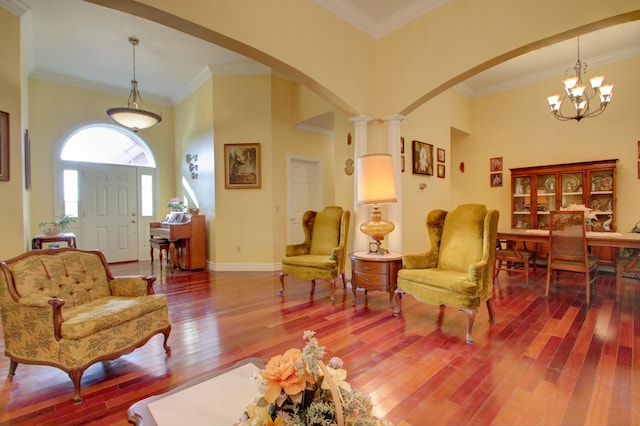 living room with a chandelier, decorative columns, hardwood / wood-style flooring, and ornamental molding