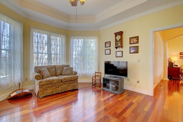 living room with hardwood / wood-style floors, ceiling fan, ornate columns, ornamental molding, and a tray ceiling