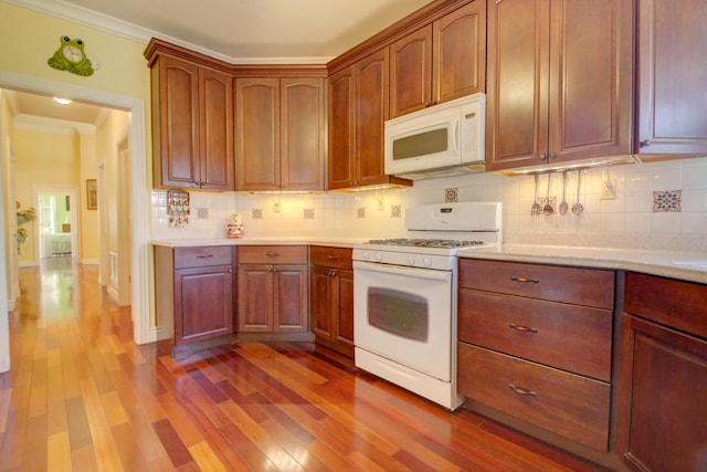 kitchen with tasteful backsplash, crown molding, light hardwood / wood-style floors, and white appliances