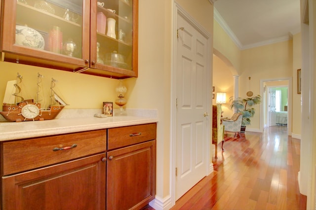 bar with light hardwood / wood-style flooring and crown molding