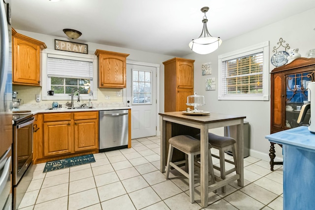 kitchen with decorative light fixtures, sink, stainless steel appliances, and a wealth of natural light