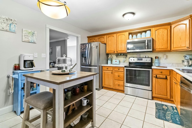 kitchen featuring light tile patterned floors, stainless steel appliances, and crown molding