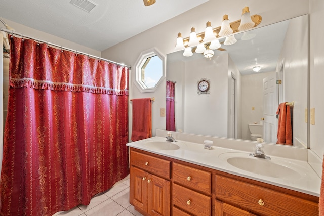 bathroom featuring tile patterned floors, vanity, toilet, and a textured ceiling