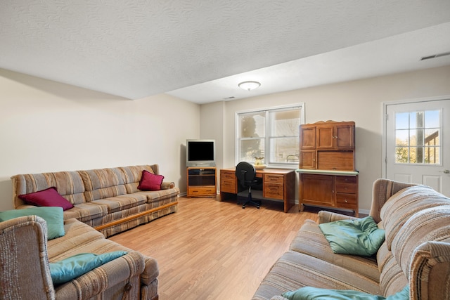 living room with a textured ceiling and light wood-type flooring