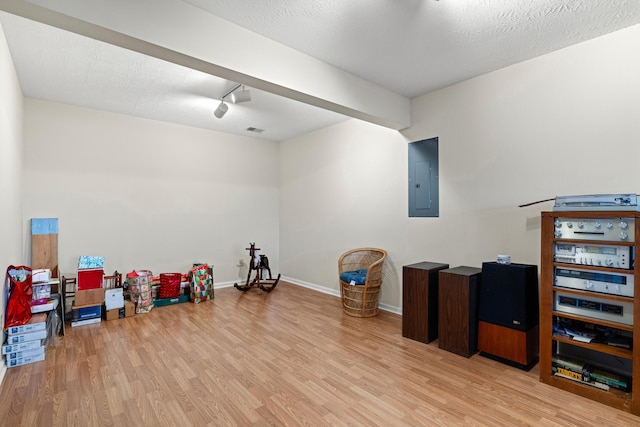 miscellaneous room with light wood-type flooring, a textured ceiling, and electric panel