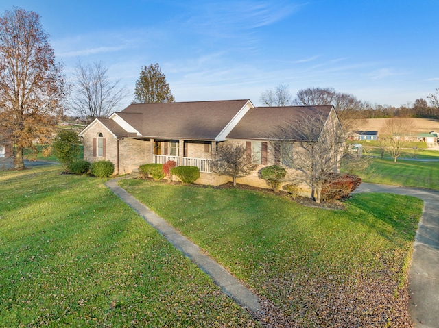 ranch-style home featuring covered porch and a front lawn