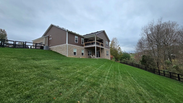 rear view of property with a lawn, central AC, and a balcony