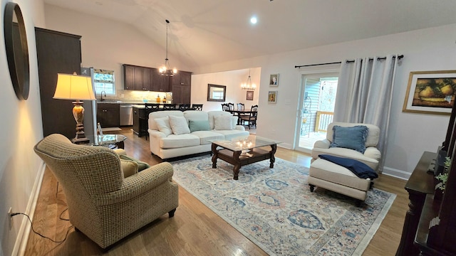 living room featuring a chandelier, hardwood / wood-style floors, lofted ceiling, and sink