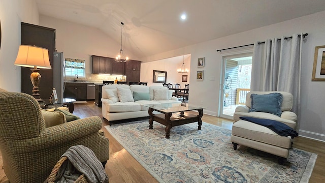 living room with a chandelier, wood-type flooring, sink, and vaulted ceiling