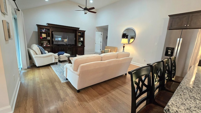 living room with hardwood / wood-style floors, high vaulted ceiling, and ceiling fan