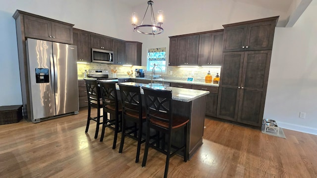 kitchen with a notable chandelier, a kitchen island, dark wood-type flooring, and appliances with stainless steel finishes