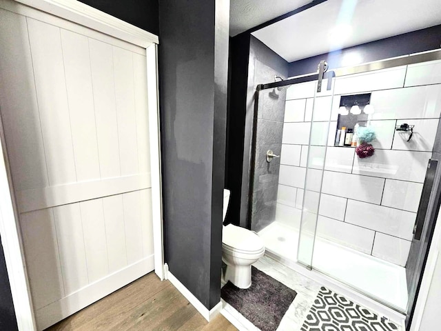 bathroom with walk in shower, toilet, and hardwood / wood-style flooring