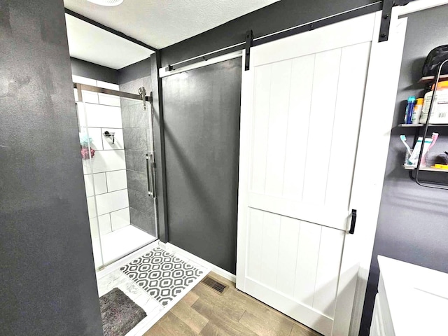 bathroom featuring a shower with shower door, a textured ceiling, and hardwood / wood-style flooring