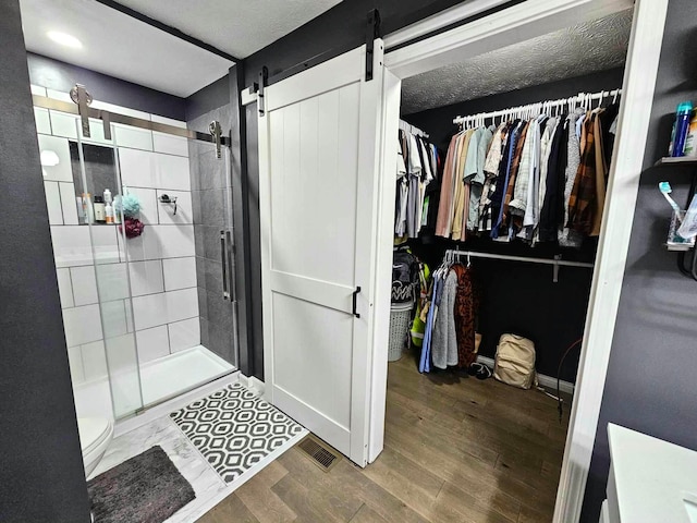 bathroom with a shower with door, a textured ceiling, and hardwood / wood-style flooring