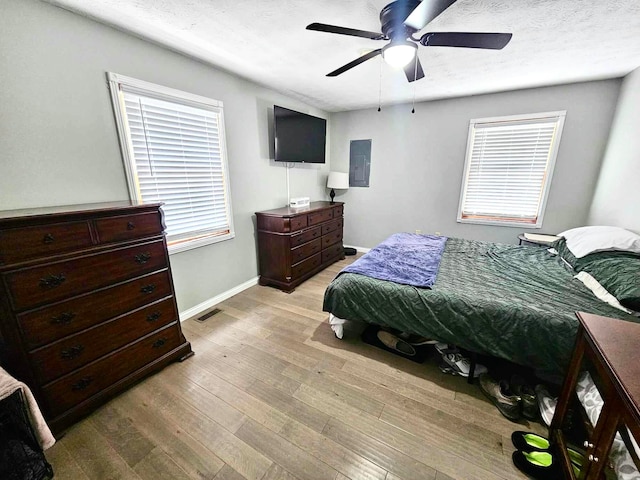 bedroom featuring electric panel, ceiling fan, and light hardwood / wood-style floors