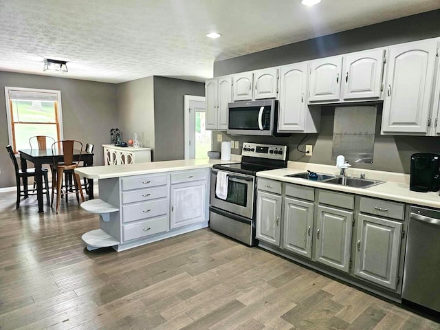 kitchen featuring kitchen peninsula, white cabinets, a healthy amount of sunlight, and appliances with stainless steel finishes