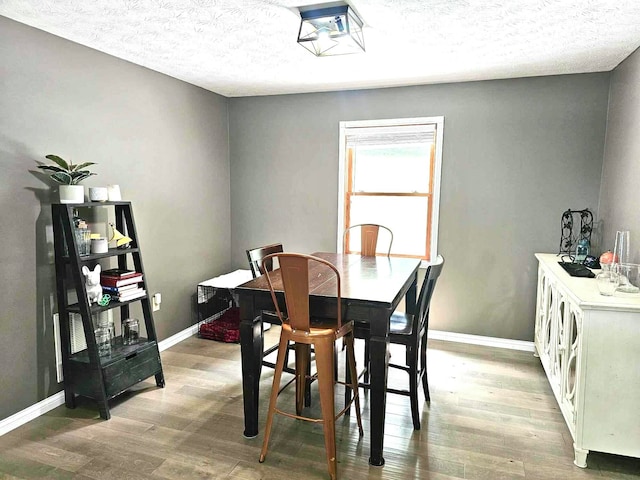 dining area featuring wood-type flooring and a textured ceiling