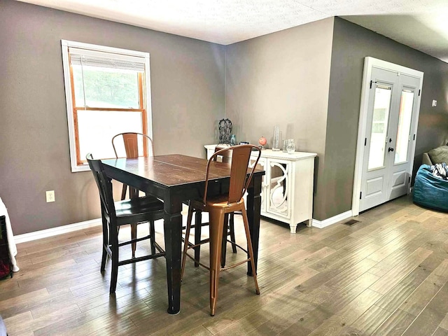 dining space featuring wood-type flooring and a textured ceiling