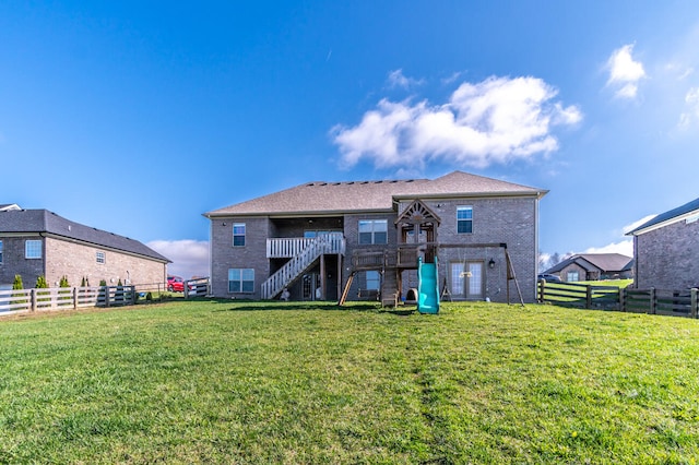 rear view of property featuring a playground and a yard