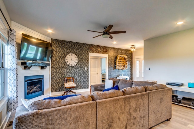 living room featuring a fireplace, light wood-type flooring, and ceiling fan