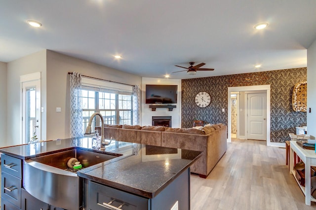 kitchen with light hardwood / wood-style floors, ceiling fan, a center island with sink, and sink