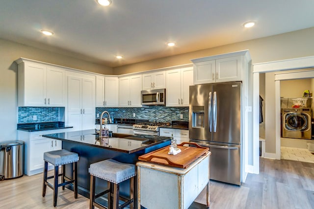 kitchen featuring washer / clothes dryer, white cabinetry, and stainless steel appliances