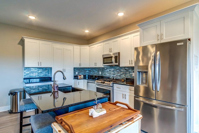 kitchen with a breakfast bar, sink, light hardwood / wood-style flooring, white cabinetry, and stainless steel appliances