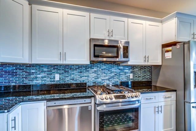 kitchen featuring dark stone counters, white cabinets, and stainless steel appliances