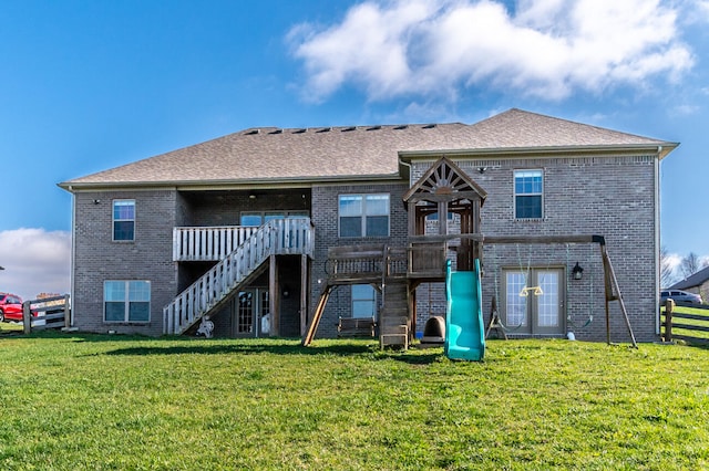 back of house featuring a playground and a lawn