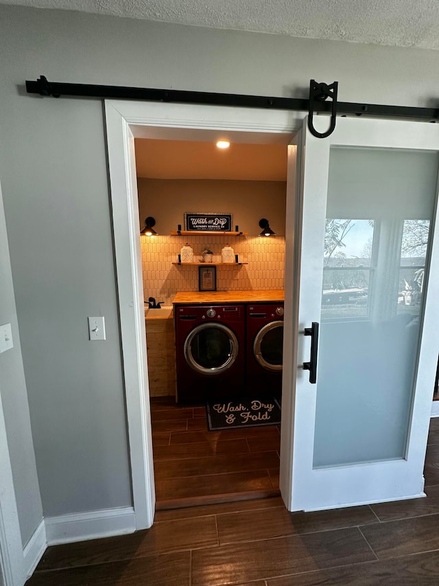 washroom with washer and dryer, a textured ceiling, a barn door, and dark wood-type flooring