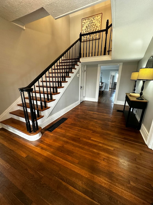 stairs with hardwood / wood-style floors and a textured ceiling