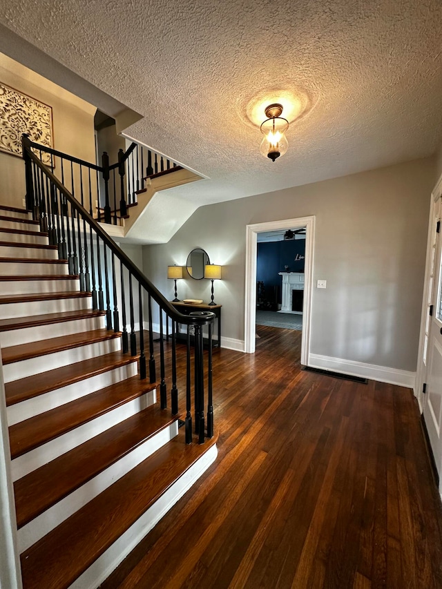 foyer entrance featuring a textured ceiling and dark hardwood / wood-style floors