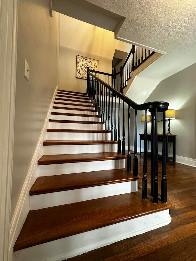 stairs featuring hardwood / wood-style floors and a textured ceiling