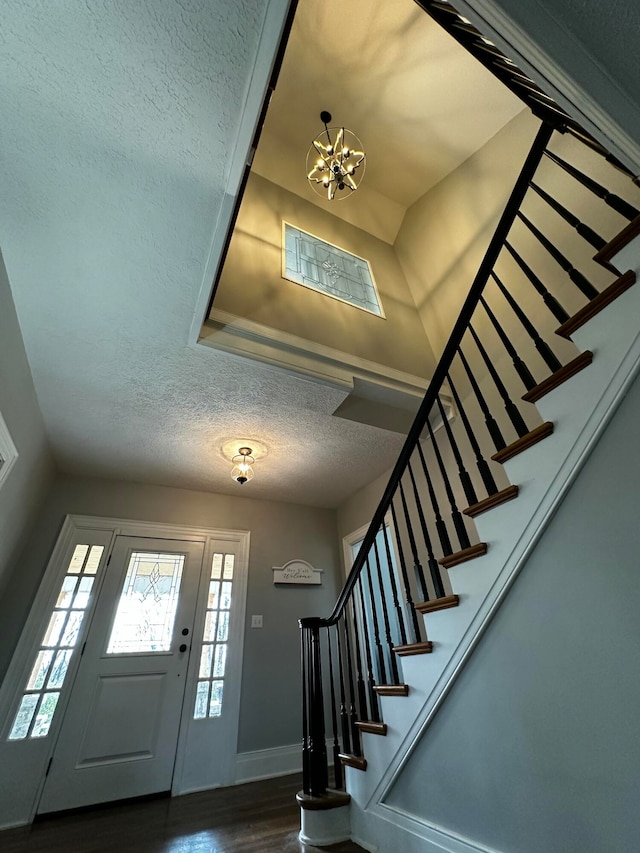 foyer entrance featuring a textured ceiling, dark hardwood / wood-style flooring, and a notable chandelier