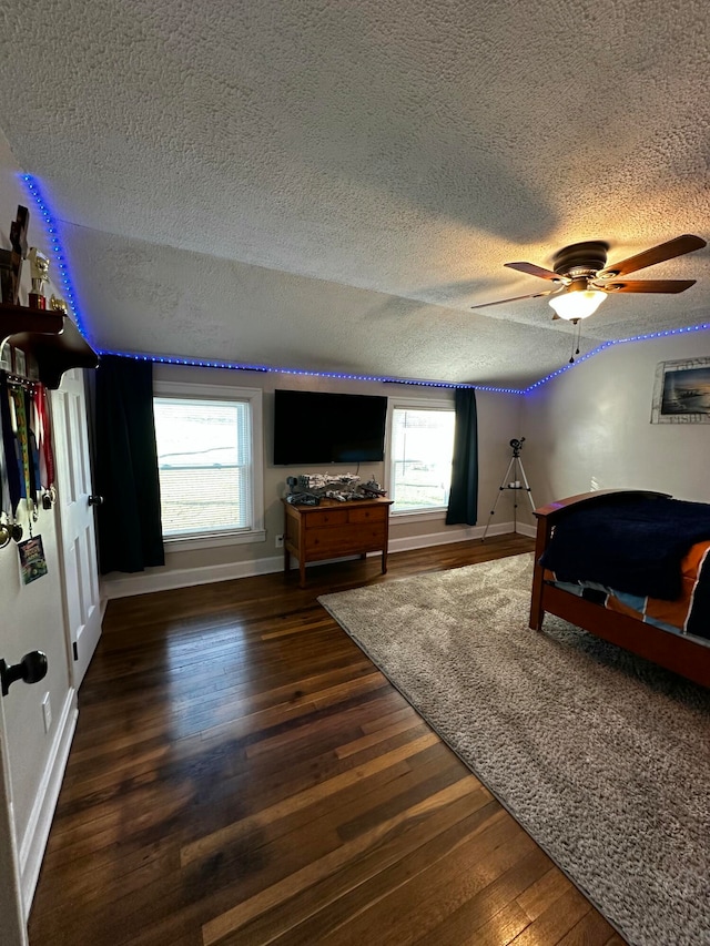 bedroom with multiple windows, a textured ceiling, ceiling fan, and dark wood-type flooring