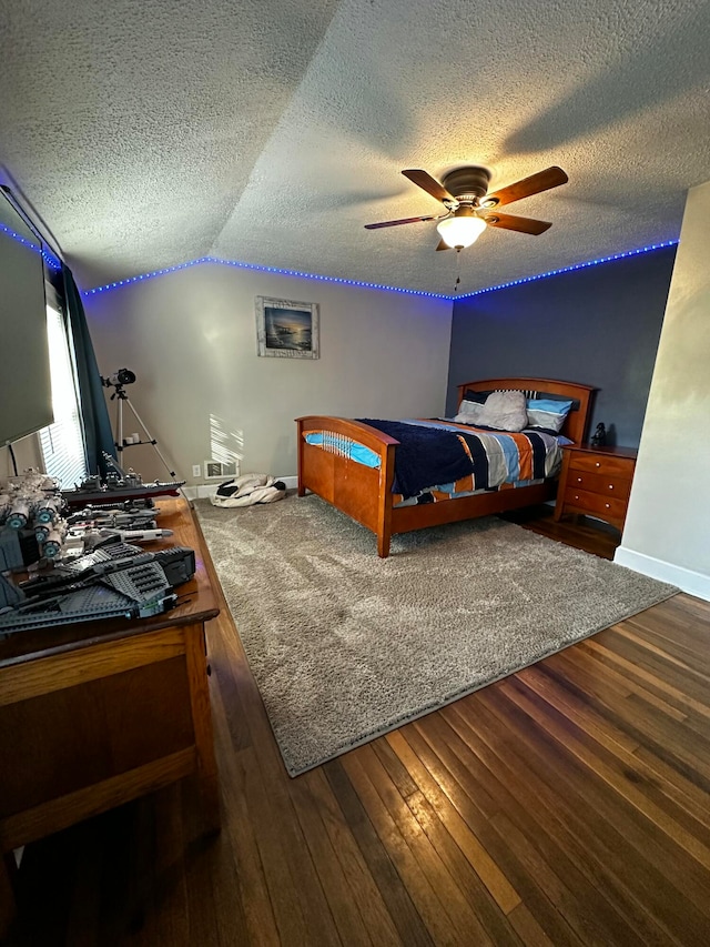 bedroom with ceiling fan, dark hardwood / wood-style flooring, lofted ceiling, and a textured ceiling