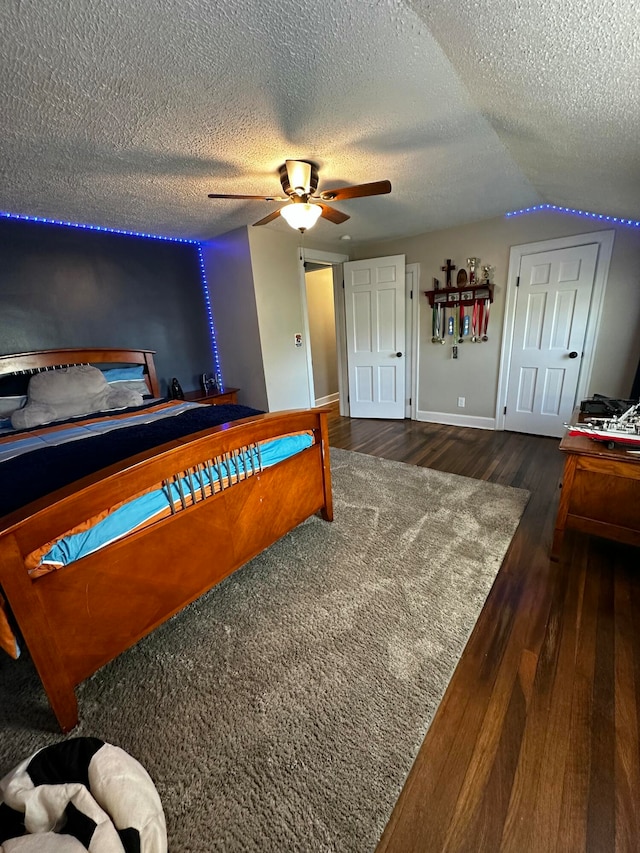 bedroom featuring a textured ceiling, vaulted ceiling, ceiling fan, and dark wood-type flooring