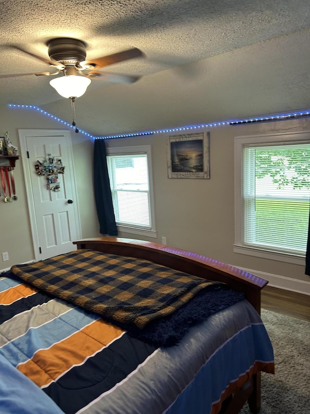 bedroom featuring ceiling fan, hardwood / wood-style floors, and a textured ceiling