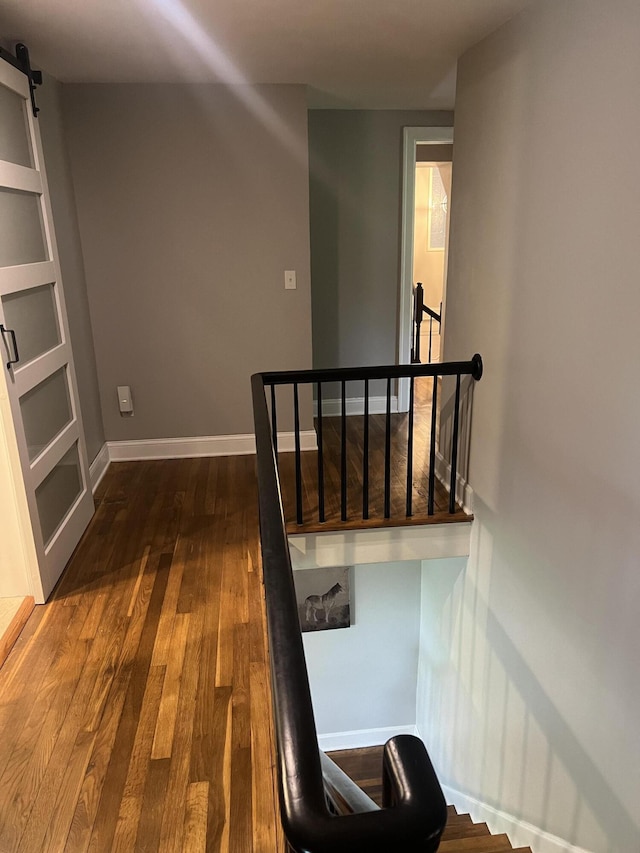 2458 High Bridge Rd, Lancaster, KY 40444 - corridor featuring a barn door, dark wood-style flooring, an upstairs landing, and baseboards