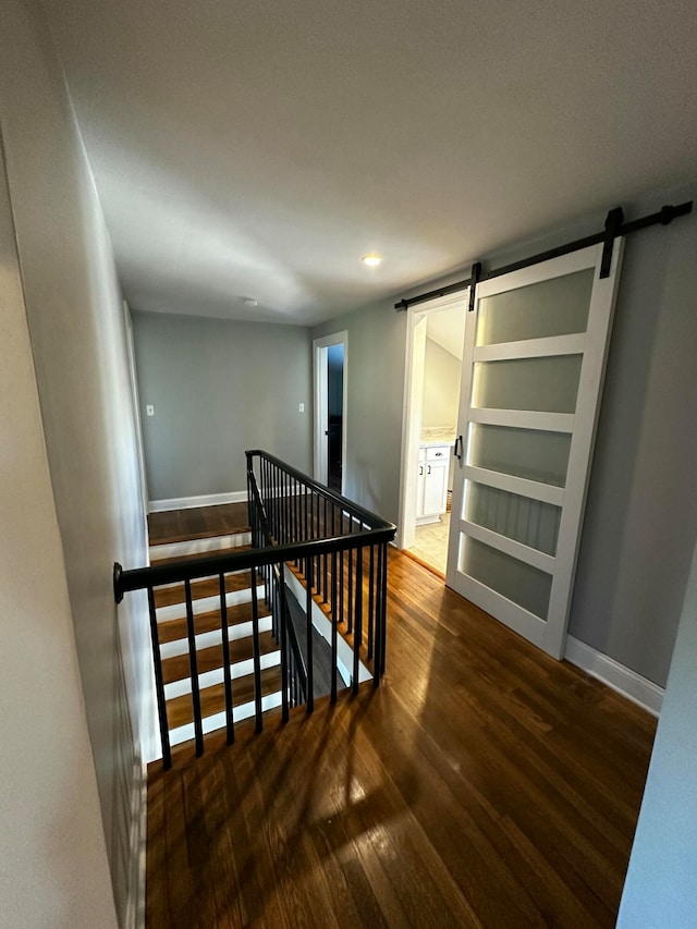 stairway with a barn door and hardwood / wood-style flooring