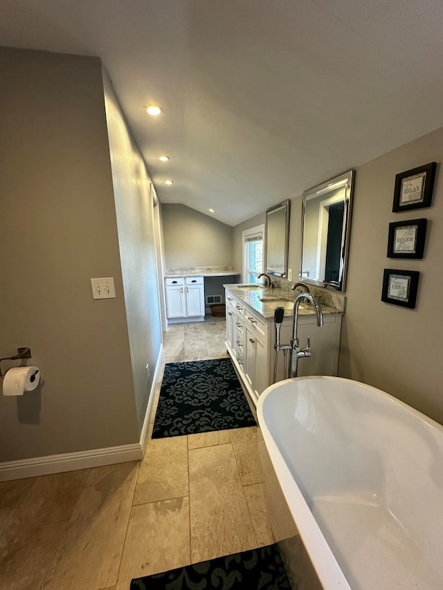 bathroom with tile patterned floors, a washtub, vanity, and vaulted ceiling