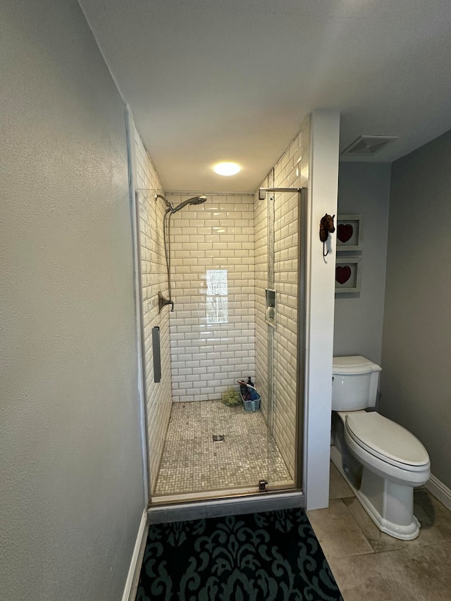 bathroom with tile patterned flooring, toilet, and a shower with door