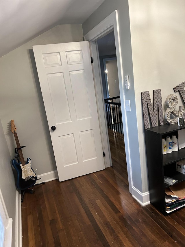 corridor with vaulted ceiling and dark hardwood / wood-style floors