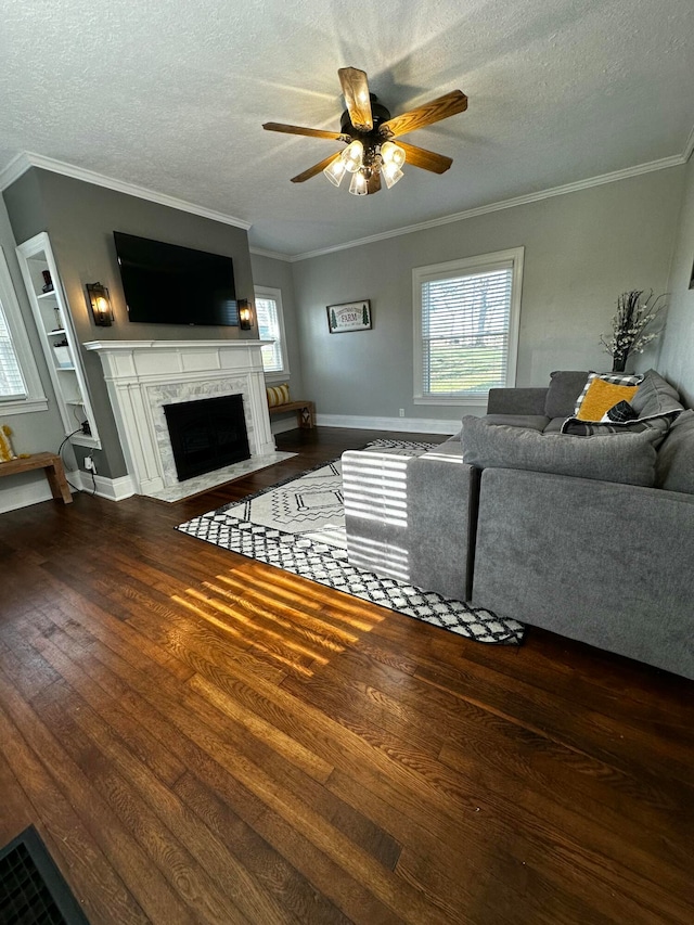 living room with ceiling fan, dark hardwood / wood-style floors, a textured ceiling, a fireplace, and ornamental molding