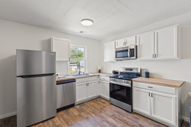 kitchen featuring a textured ceiling, stainless steel appliances, sink, dark hardwood / wood-style floors, and white cabinetry